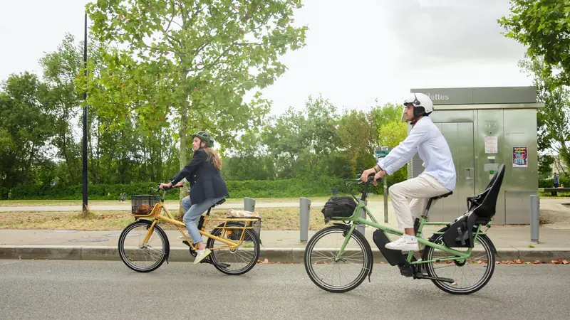 Deux cyclistes à vélo dans une rue arborée