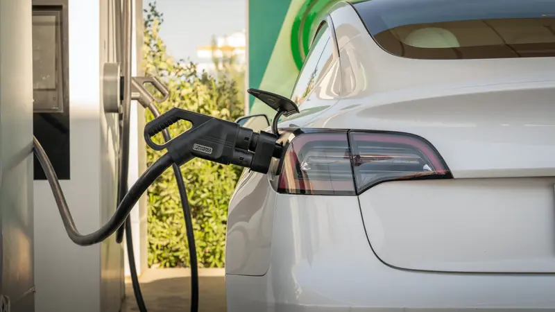 Voiture électrique blanche branchée sur une borne de recharge