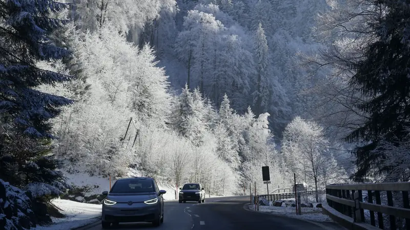 Voiture électrique roulant sur une route enneigée en hiver