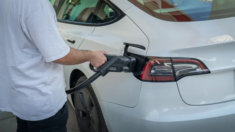 Conducteur qui branche le câble de recharge sur sa voiture