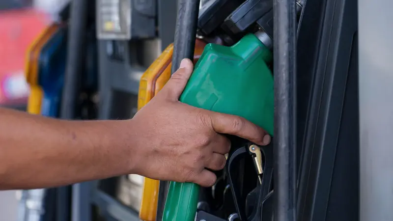 Main qui tient un pistolet de pompe à carburant
