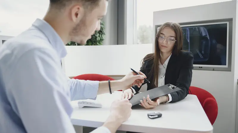Client et conseillère qui signent des documents dans une concession
