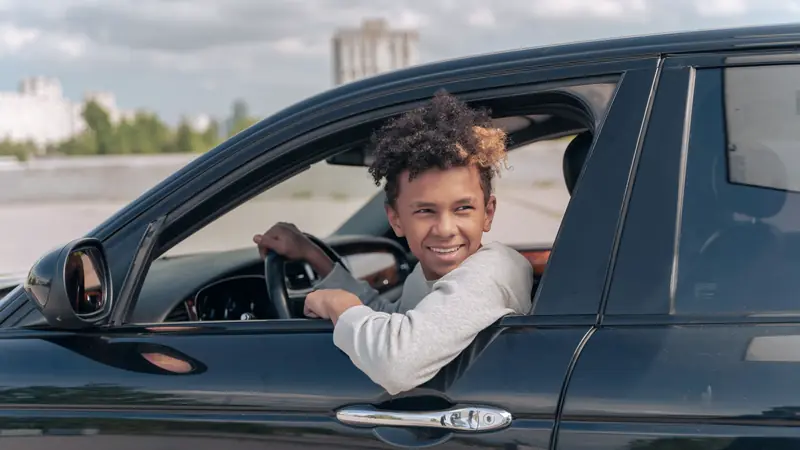 Jeune conducteur souriant au volant d'une voiture