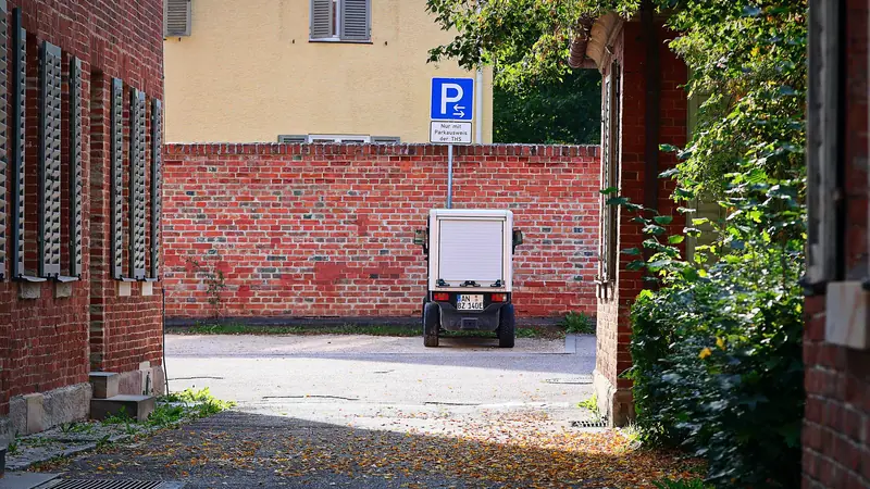 Petit véhicule urbain garé devant un mur de briques